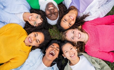 Multiracial group of young women in circle smiling at camera together